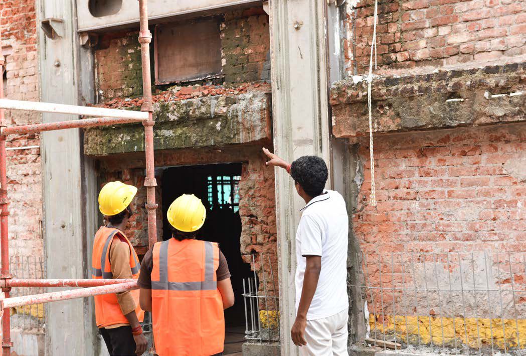 Site engineers reviewing the exposed load-bearing wall at the Bhawan