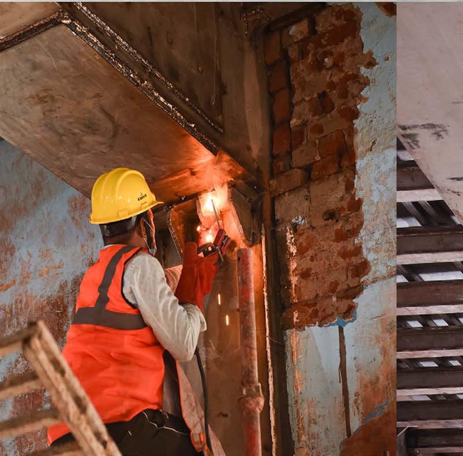 Site worker welding a stainless steel member inside the hall